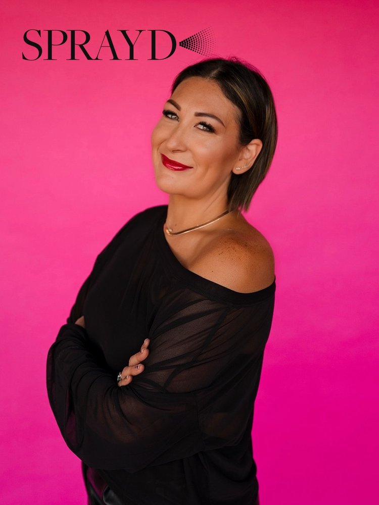 Ashlee Bivins of Sprayd smiling against a hot pink wall