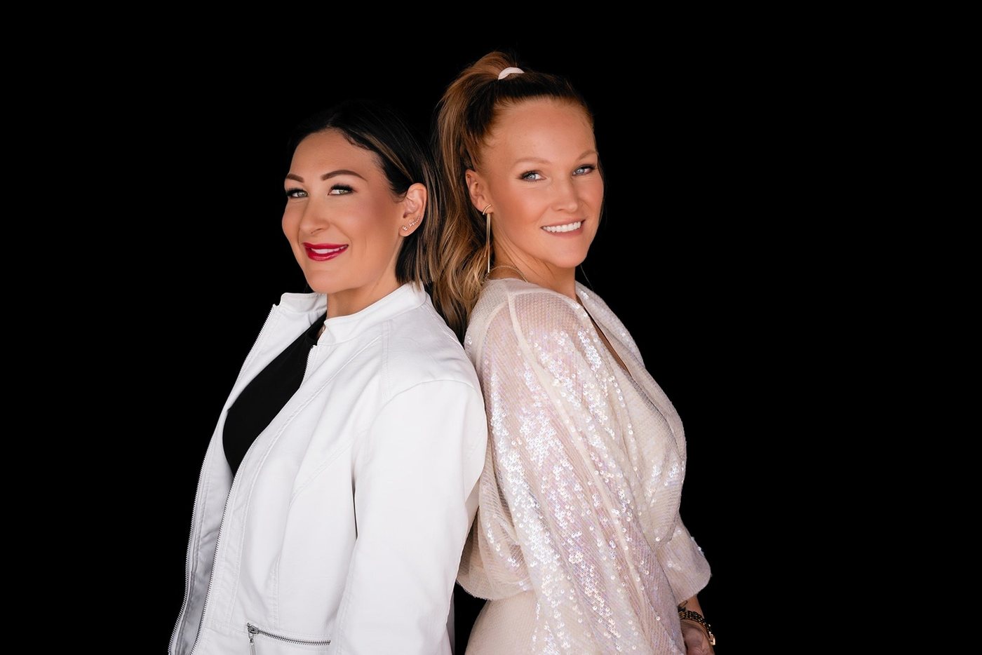 Ashlee Bivins and Erin Tietsort standing back to back, smiling, against a black background